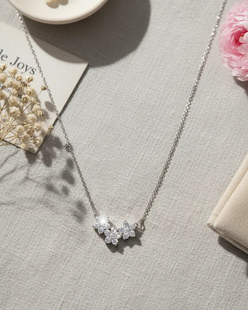 Silver floral crystal pendant necklace displayed on a soft beige fabric with aesthetic props, showing its shine and intricate detailing from Shinora