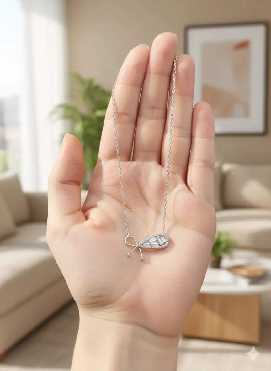Hand holding Lumina Bow Pendant – luxurious silver jewelry with crystal accents, perfect for gifting. Shinora Lumina Bow Pendant Necklace – minimal yet sophisticated silver bow pendant for women from Shinora