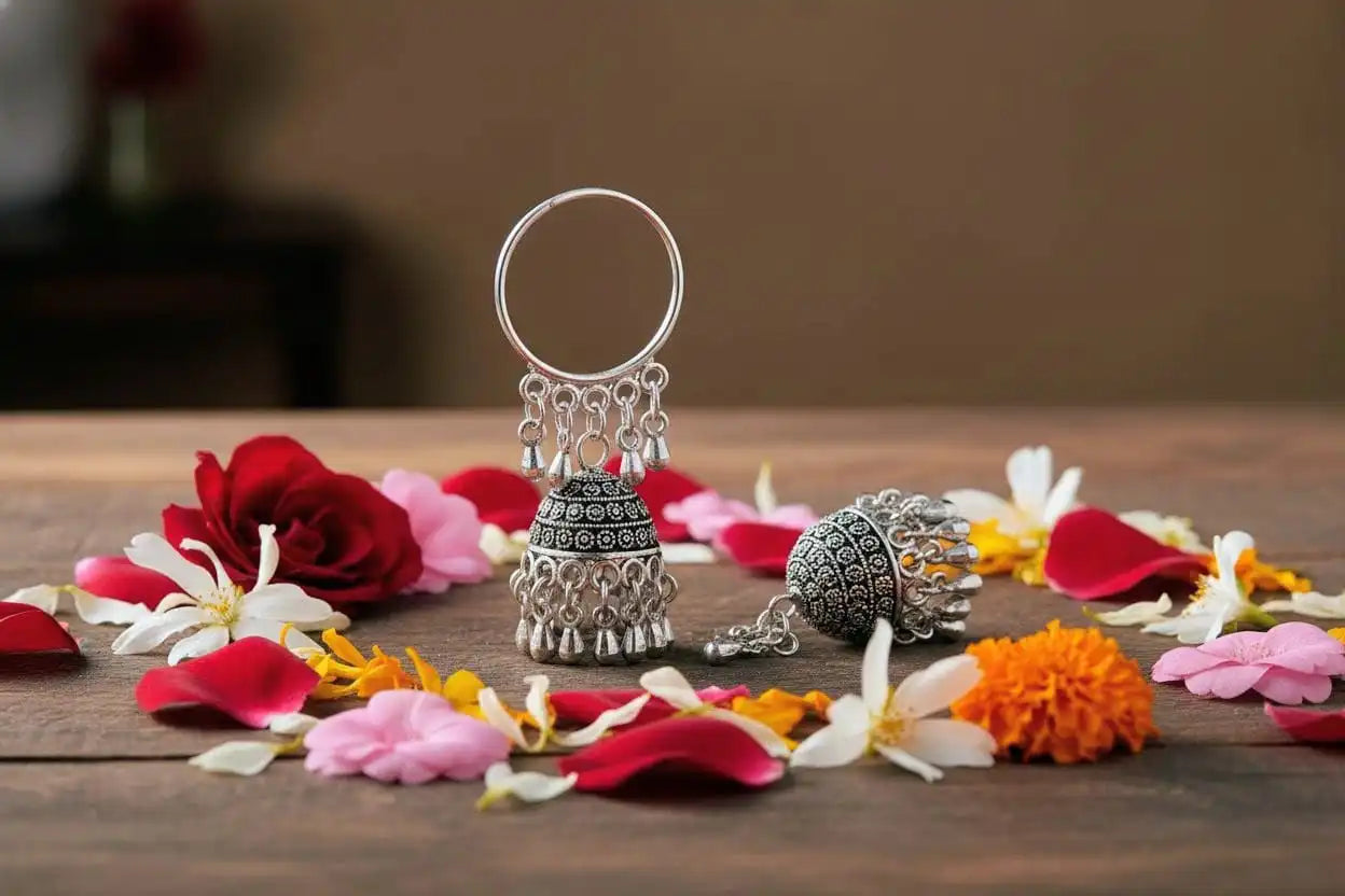 Mayuri Jhumka – oxidized silver hoop jhumka earrings with intricate detailing and ghungroo drops displayed on a wooden surface decorated with rose and jasmine petals from Shinora