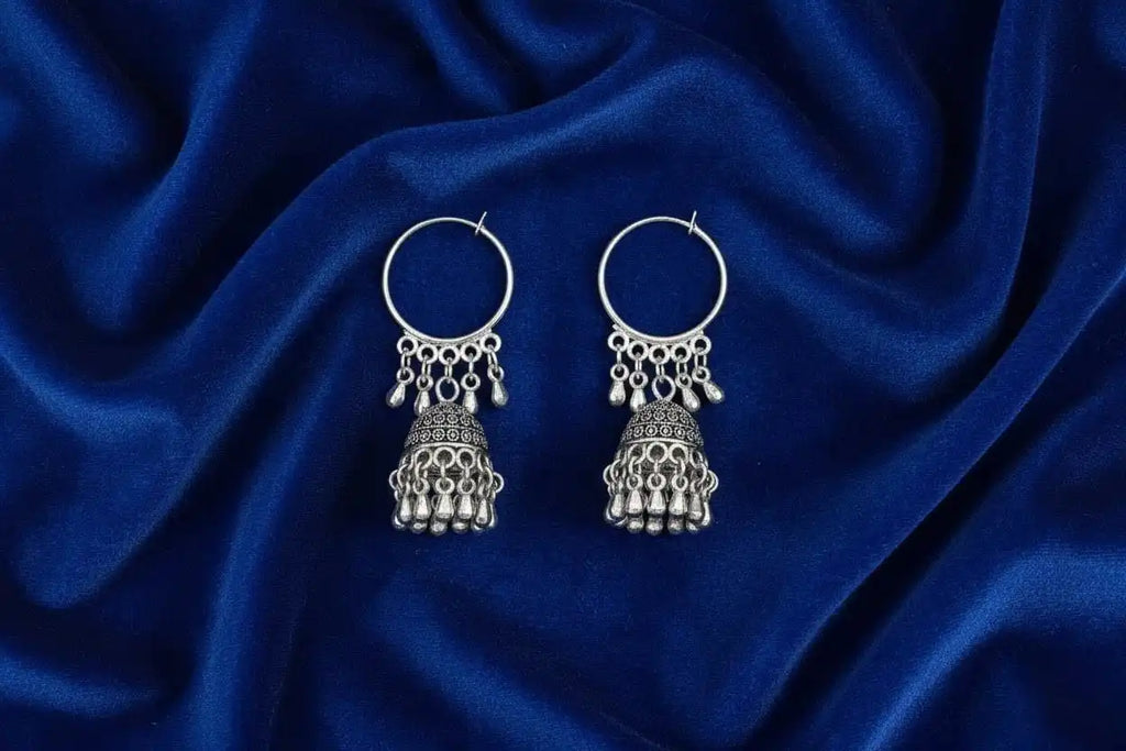 Mayuri Jhumka – oxidized silver hoop jhumka earrings placed on deep blue velvet fabric, showcasing traditional Indian craftsmanship from Shinora
