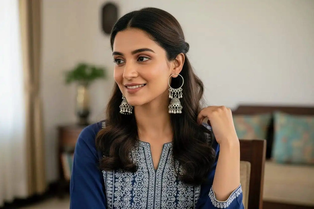 Woman smiling while wearing Mayuri Jhumka – oxidized silver hoop jhumka earrings styled with a navy embroidered kurta in a home setting from Shinora