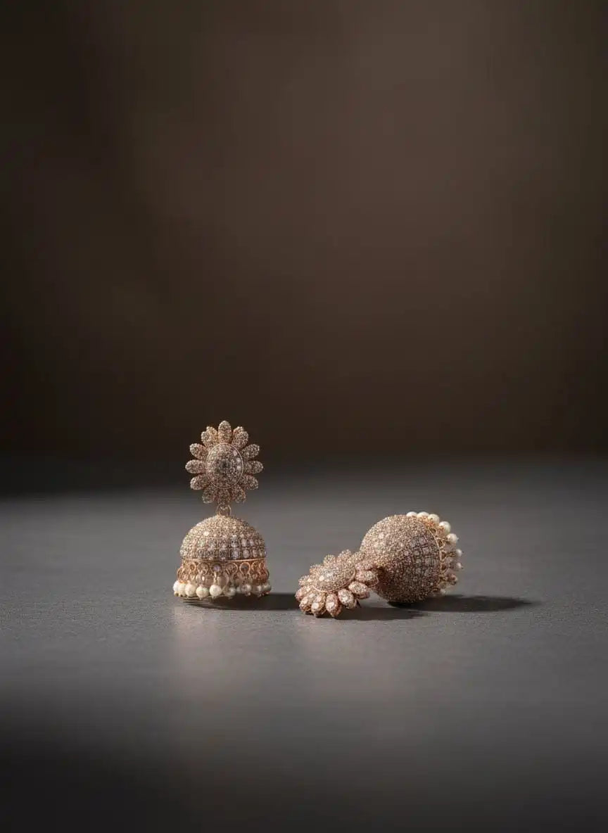 Noor Jhumka – rose-gold diamond-studded jhumka earrings with pearl danglers displayed on a dark matte surface from Shinora
