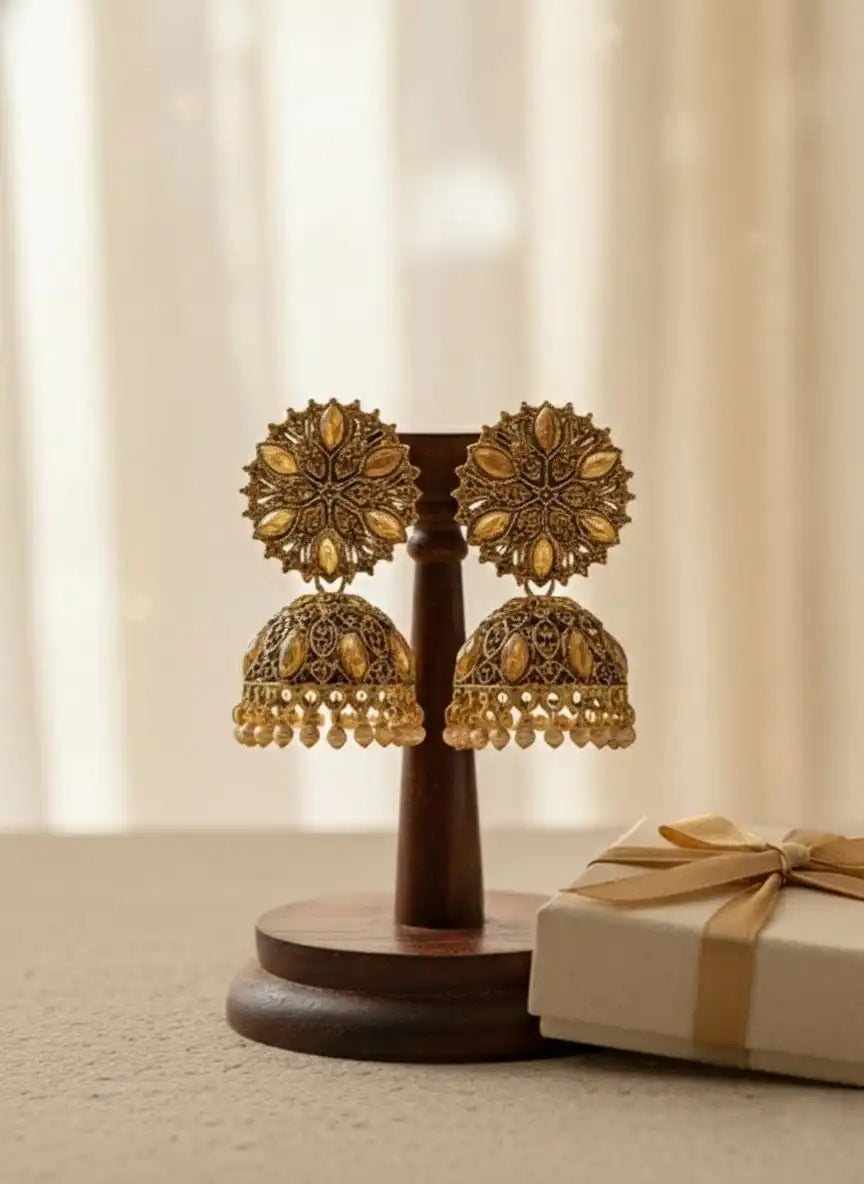 Heer Jhumka – antique gold-plated floral jhumka earrings displayed on a wooden stand with a gift box, traditional Indian jewelry from Shinora