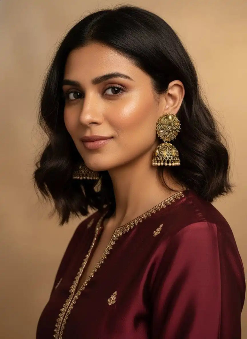 Model wearing Heer Jhumka – gold-plated floral jhumka earrings styled with maroon ethnic outfit, festive traditional jewelry from Shinora