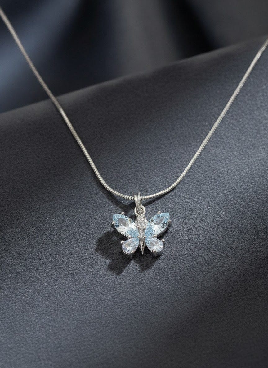 Detailed close-up of The Fluttering Charm butterfly necklace with shimmering clear stones and polished silver chain, photographed on a light background by shinora