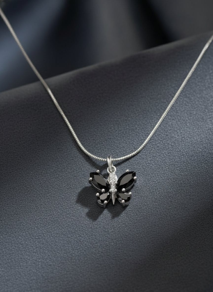 Close-up of The Fluttering Charm butterfly pendant necklace featuring glossy black stones on a silver chain, displayed on a dark background from Shinora