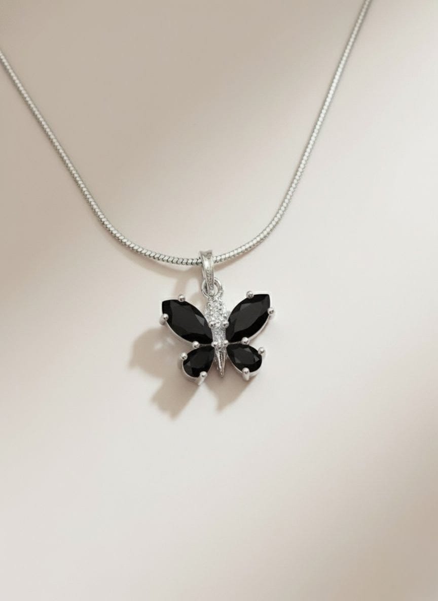 Detailed close-up of The Fluttering Charm black butterfly pendant necklace with polished silver chain, captured on a neutral background from Shinora