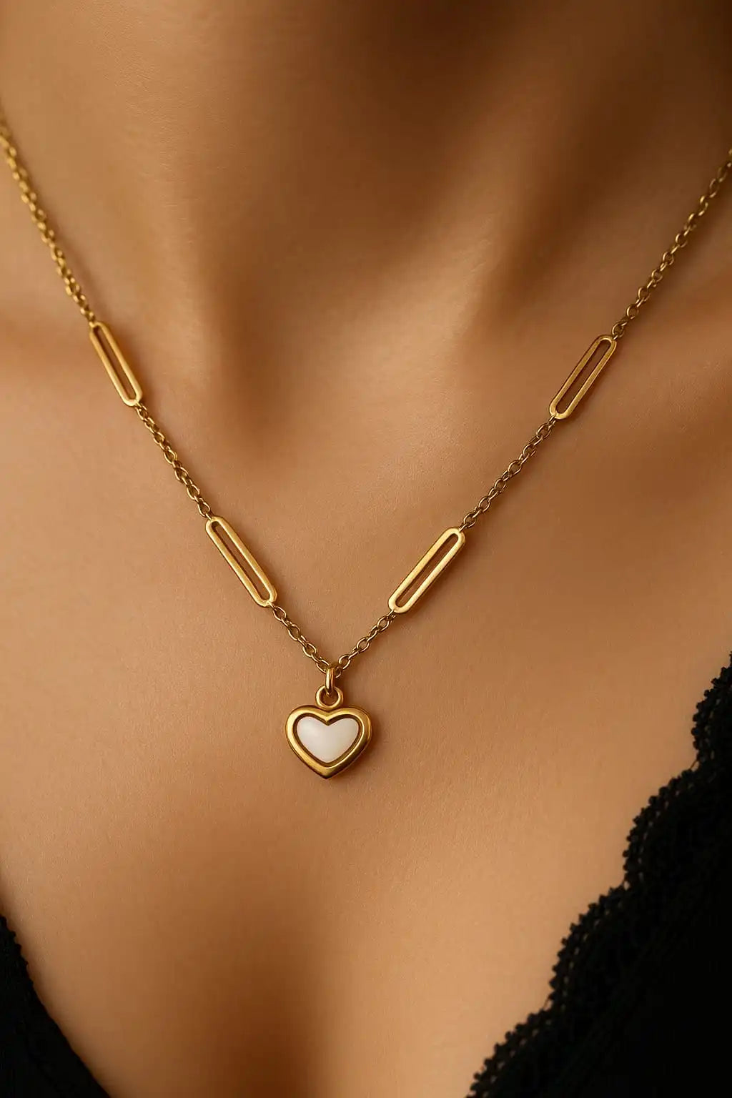 Gold heart necklace with floral white enamel pendant shown in a close-up on neckline, anti-tarnish jewelry design from shinora