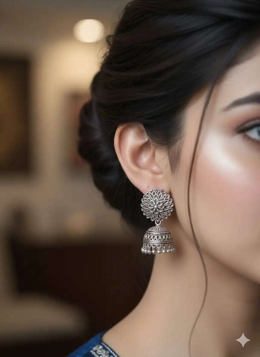 Close-up view of oxidised silver jhumka worn on the ear, showing intricate floral stud and dome design from Shinora