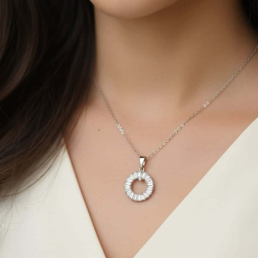 Silver necklace with a circular pendant worn by a person from Shinora